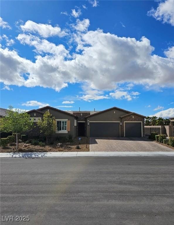 ranch-style house with stucco siding, an attached garage, and decorative driveway