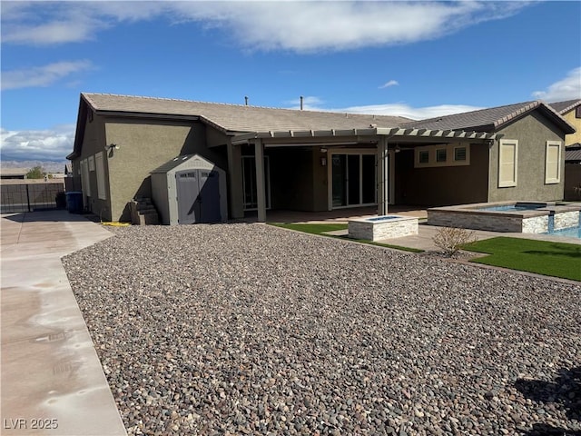 rear view of property with a patio, fence, a shed, an in ground hot tub, and stucco siding