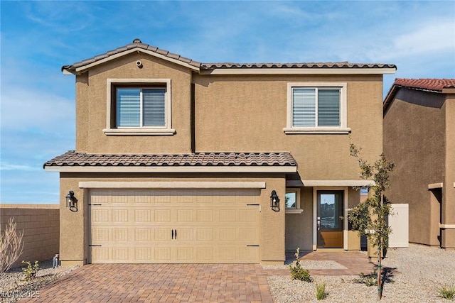 view of front facade featuring decorative driveway, a tile roof, an attached garage, and stucco siding