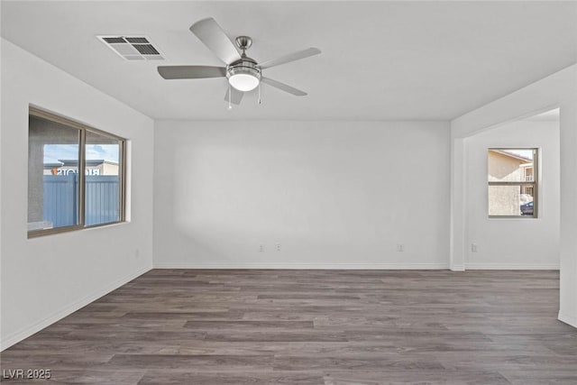 spare room featuring a healthy amount of sunlight, a ceiling fan, visible vents, and wood finished floors