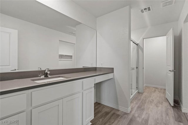 bathroom featuring wood finished floors, vanity, baseboards, visible vents, and a shower stall