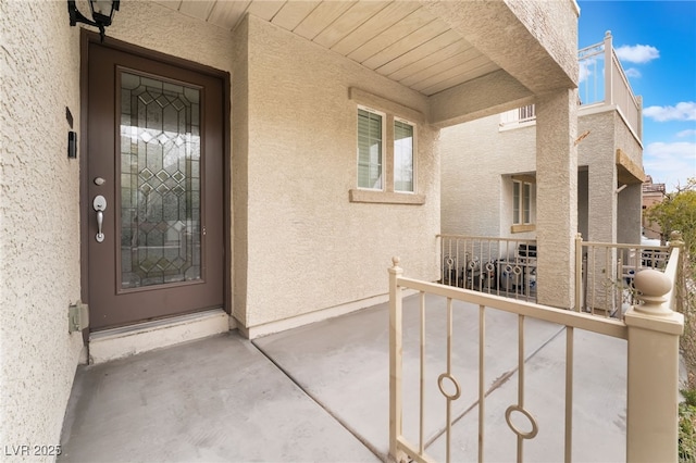 property entrance featuring a balcony and stucco siding