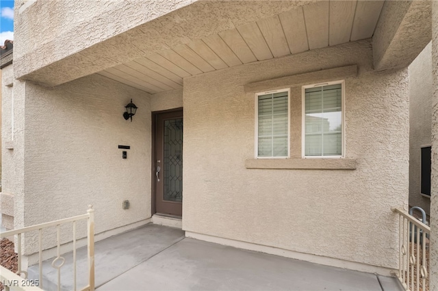 entrance to property featuring a patio and stucco siding