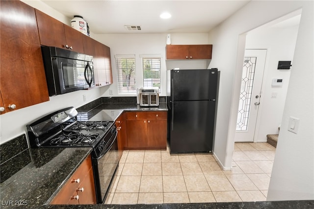 kitchen featuring light tile patterned flooring, visible vents, baseboards, black appliances, and dark stone countertops