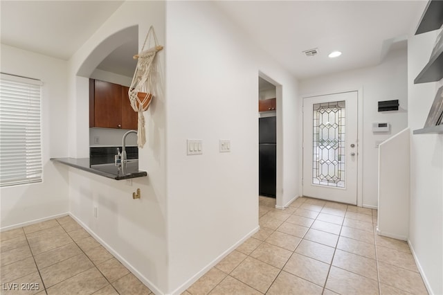 entryway with light tile patterned floors, baseboards, and visible vents