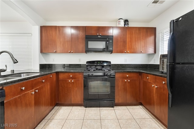 kitchen with light tile patterned floors, visible vents, dark stone counters, black appliances, and a sink