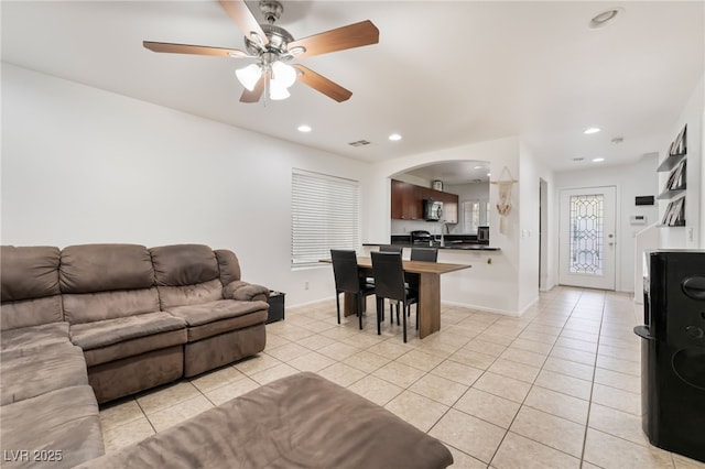 living room with light tile patterned floors, arched walkways, recessed lighting, visible vents, and baseboards