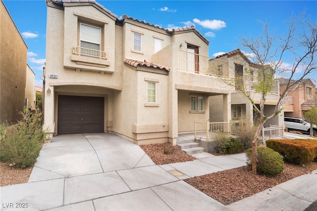 view of front facade with stucco siding, concrete driveway, an attached garage, a balcony, and a tiled roof