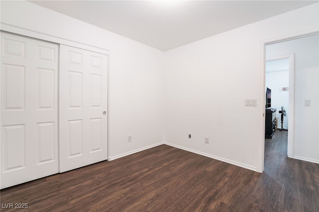 unfurnished bedroom featuring a closet, dark wood finished floors, and baseboards