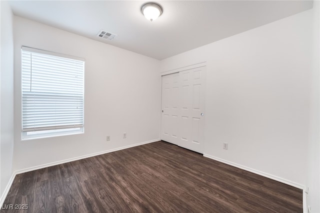 unfurnished room featuring dark wood-style floors, visible vents, and baseboards