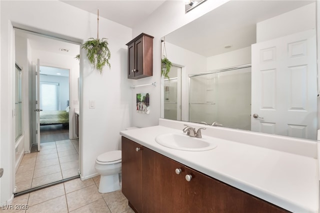 bathroom featuring tile patterned flooring, vanity, toilet, and an enclosed shower