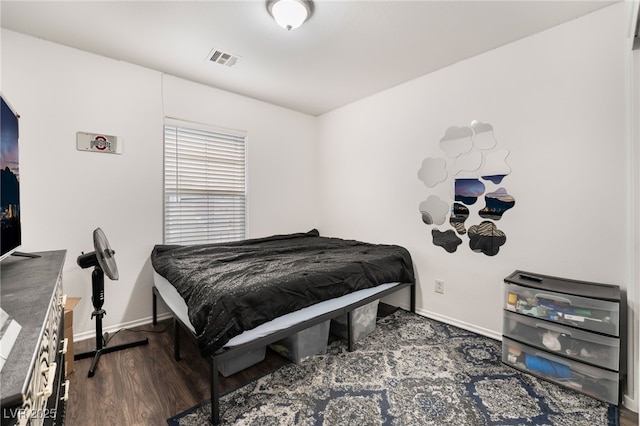 bedroom with baseboards, visible vents, and wood finished floors