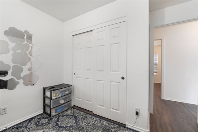 bedroom featuring a closet, baseboards, and dark wood-style flooring