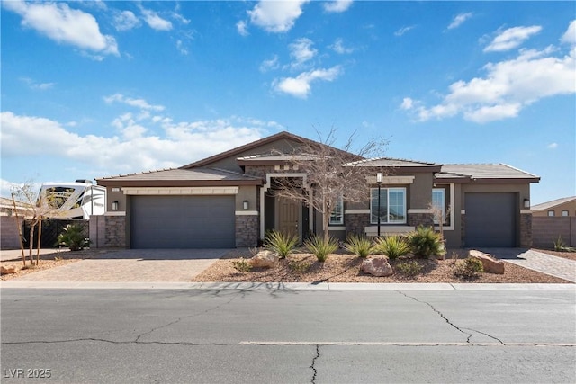 view of front of property featuring decorative driveway, stucco siding, fence, a garage, and stone siding