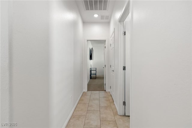 hall featuring visible vents, baseboards, and light tile patterned flooring