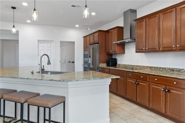 kitchen with visible vents, wall chimney exhaust hood, a breakfast bar area, stainless steel appliances, and a sink