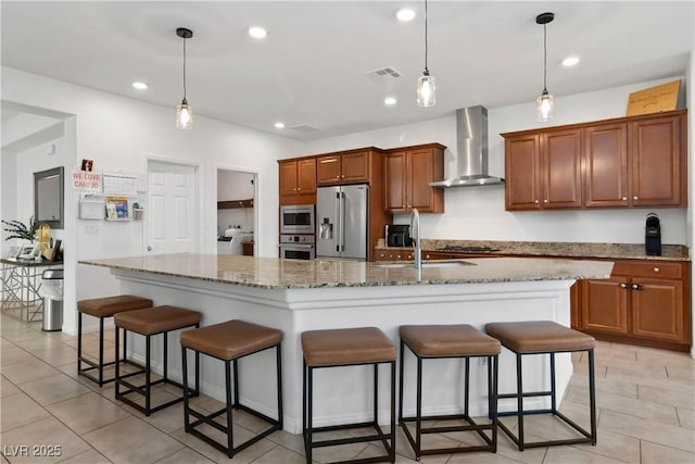 kitchen with wall chimney exhaust hood, a breakfast bar area, stainless steel appliances, and recessed lighting