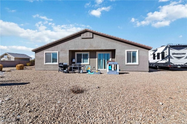 rear view of house featuring stucco siding