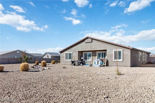 rear view of property featuring a patio, fence, and stucco siding