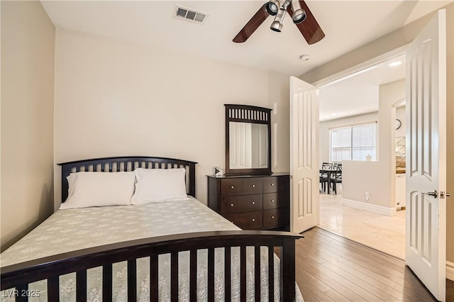 bedroom featuring baseboards, visible vents, ceiling fan, and hardwood / wood-style floors