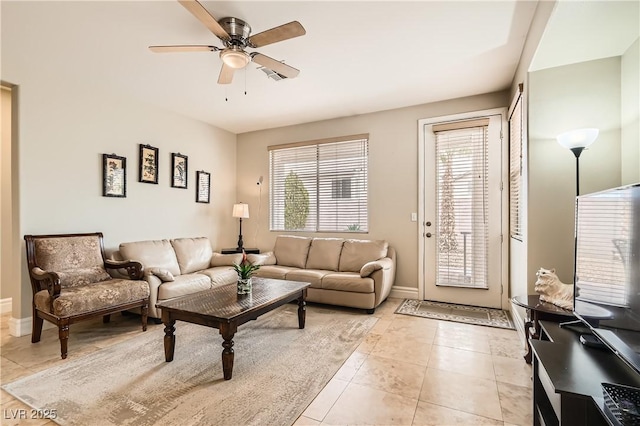 living area with a ceiling fan, baseboards, and light tile patterned floors