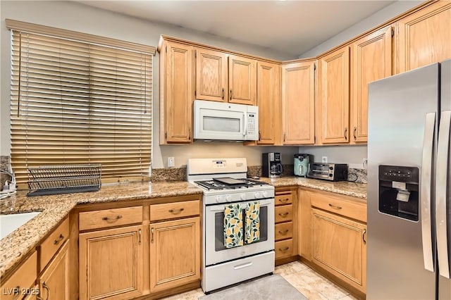 kitchen featuring light stone counters, a toaster, light tile patterned floors, light brown cabinets, and white appliances