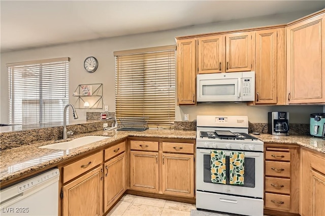 kitchen with light tile patterned floors, white appliances, a sink, and light stone counters