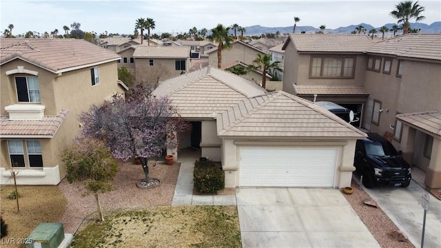 multi unit property featuring an attached garage, a tile roof, a residential view, and concrete driveway