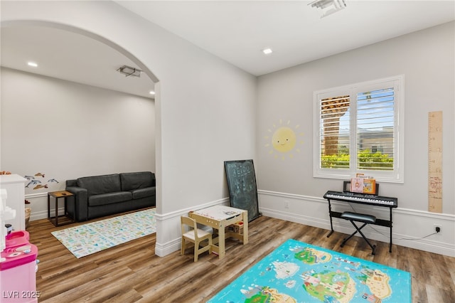 recreation room with visible vents, arched walkways, and wood finished floors