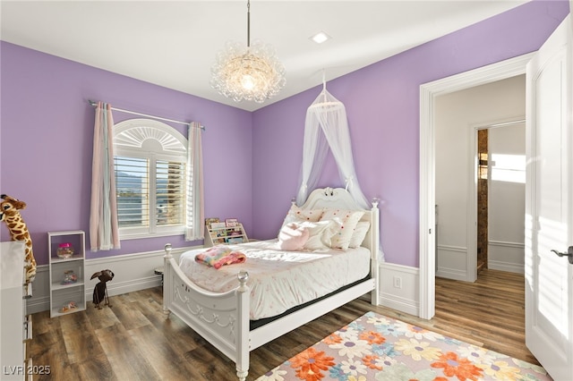 bedroom with multiple windows, wood finished floors, and an inviting chandelier