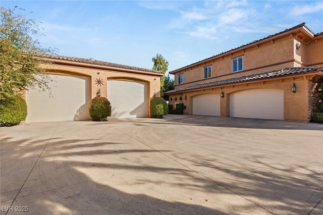 mediterranean / spanish-style home with a garage, driveway, a tile roof, and stucco siding