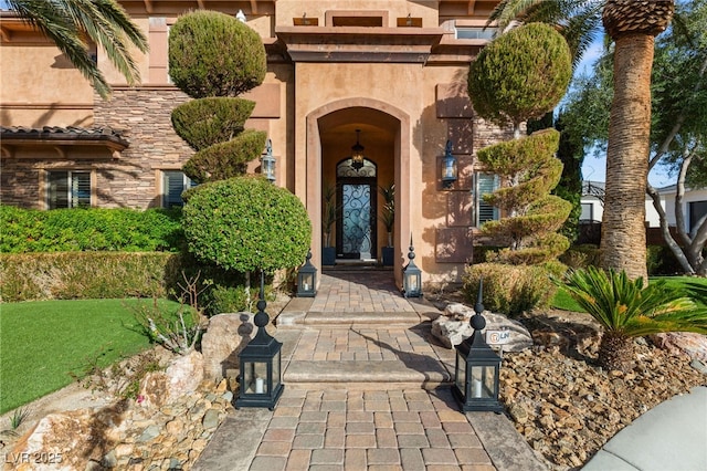 view of exterior entry featuring stone siding and stucco siding