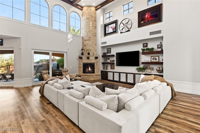 living room with visible vents, a stone fireplace, and wood finished floors