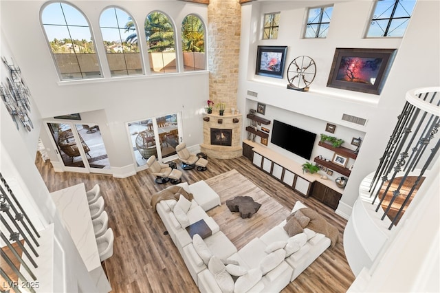 living area with a large fireplace, visible vents, a towering ceiling, stairway, and a wealth of natural light