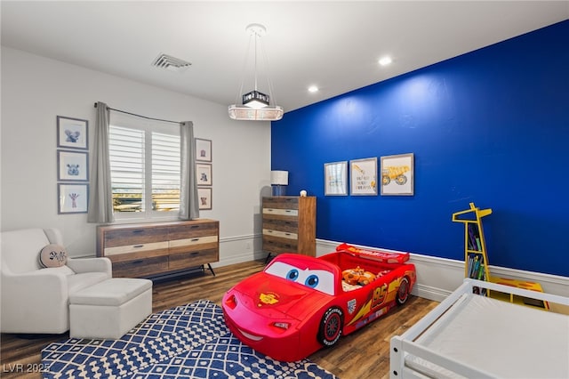 bedroom featuring wood finished floors, visible vents, and baseboards