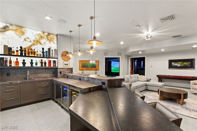 bar featuring a sink, visible vents, decorative backsplash, and indoor wet bar