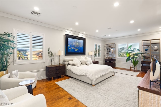 bedroom with recessed lighting, wood finished floors, visible vents, and crown molding