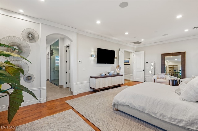 bedroom featuring arched walkways, recessed lighting, baseboards, ornamental molding, and light wood-type flooring