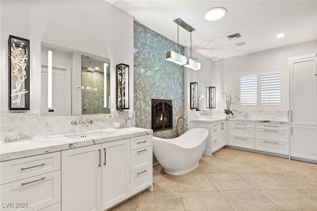 full bath featuring visible vents, a sink, tile walls, and a fireplace