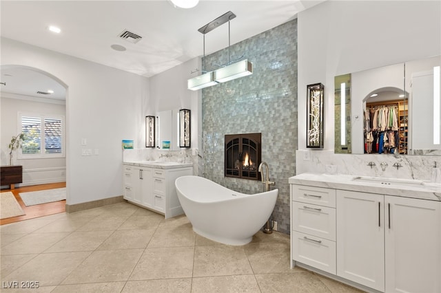 full bath with a fireplace, a sink, tile walls, visible vents, and tile patterned floors