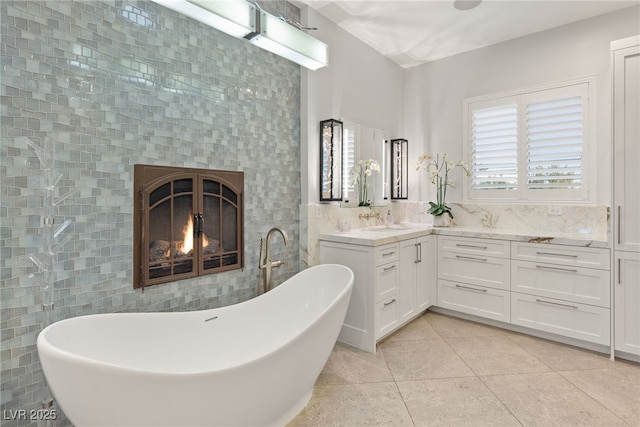 bathroom with vanity, tile walls, a soaking tub, tile patterned floors, and a glass covered fireplace