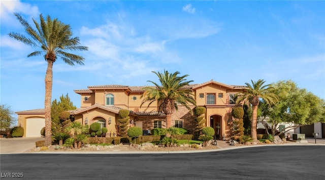 mediterranean / spanish-style house with driveway, a tiled roof, and stucco siding