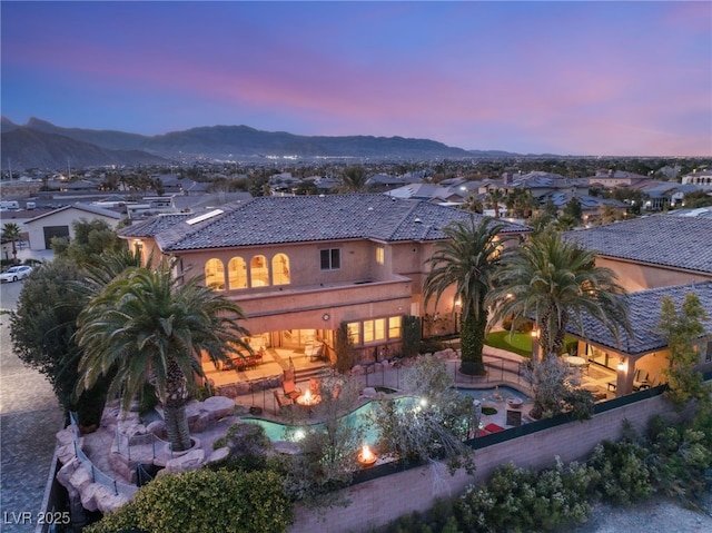 rear view of house featuring a tiled roof, fence, a patio area, a mountain view, and stucco siding