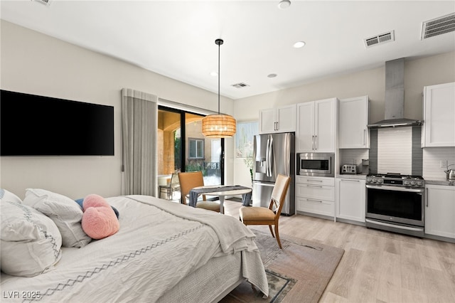 bedroom with light wood-style floors, stainless steel fridge, and visible vents