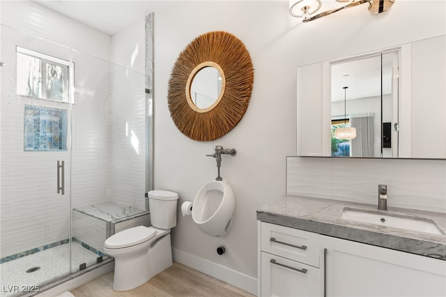 bathroom with toilet, wood finished floors, vanity, baseboards, and a shower stall