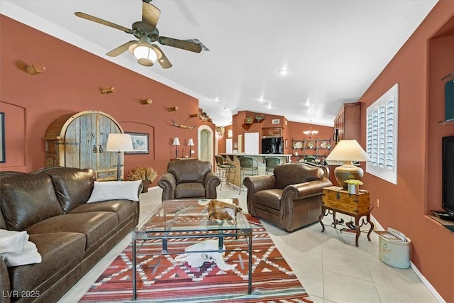 living area with visible vents, arched walkways, lofted ceiling, light tile patterned flooring, and ceiling fan with notable chandelier