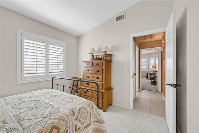 bedroom with light carpet, vaulted ceiling, visible vents, and baseboards