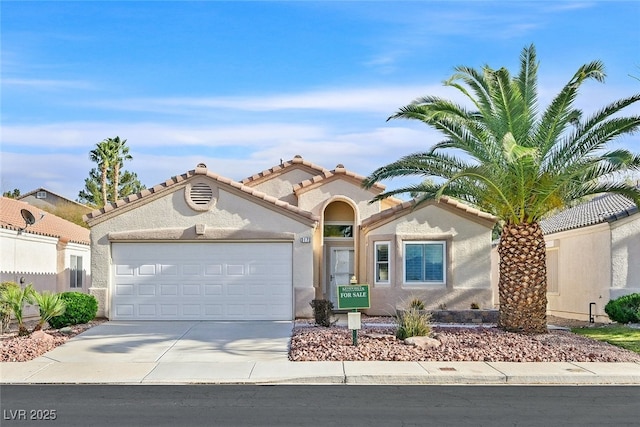 mediterranean / spanish-style house featuring a garage, concrete driveway, a tiled roof, and stucco siding