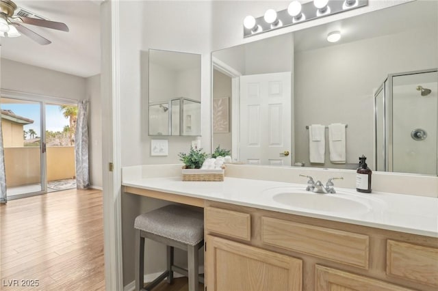 bathroom with a shower stall, vanity, ceiling fan, and wood finished floors