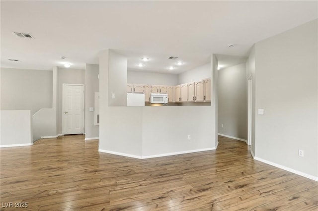 empty room featuring visible vents, baseboards, and hardwood / wood-style flooring